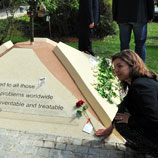 Photo: UNODC staff member puts a flower at the "Tree of Hope" monument in remembrance of those affected by drug addiction