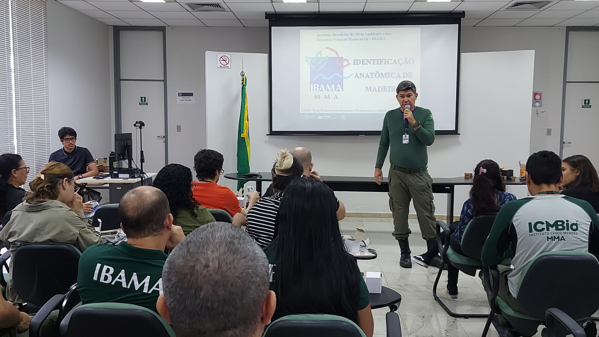 Técnico do Ibama apresenta técnicas de identificação de madeira a representantes de diversas instituições em uma sala.