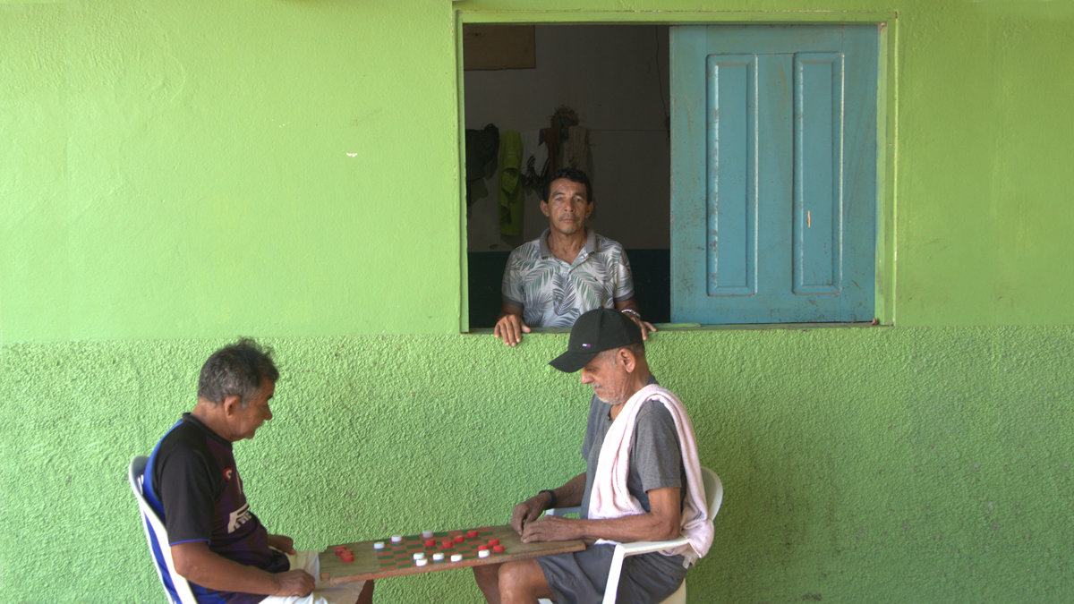 Two men are playing a game, one is looking out the window