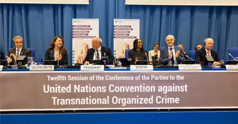 Photo of UNTOC COP11 opening session. A panel of three women and two men.